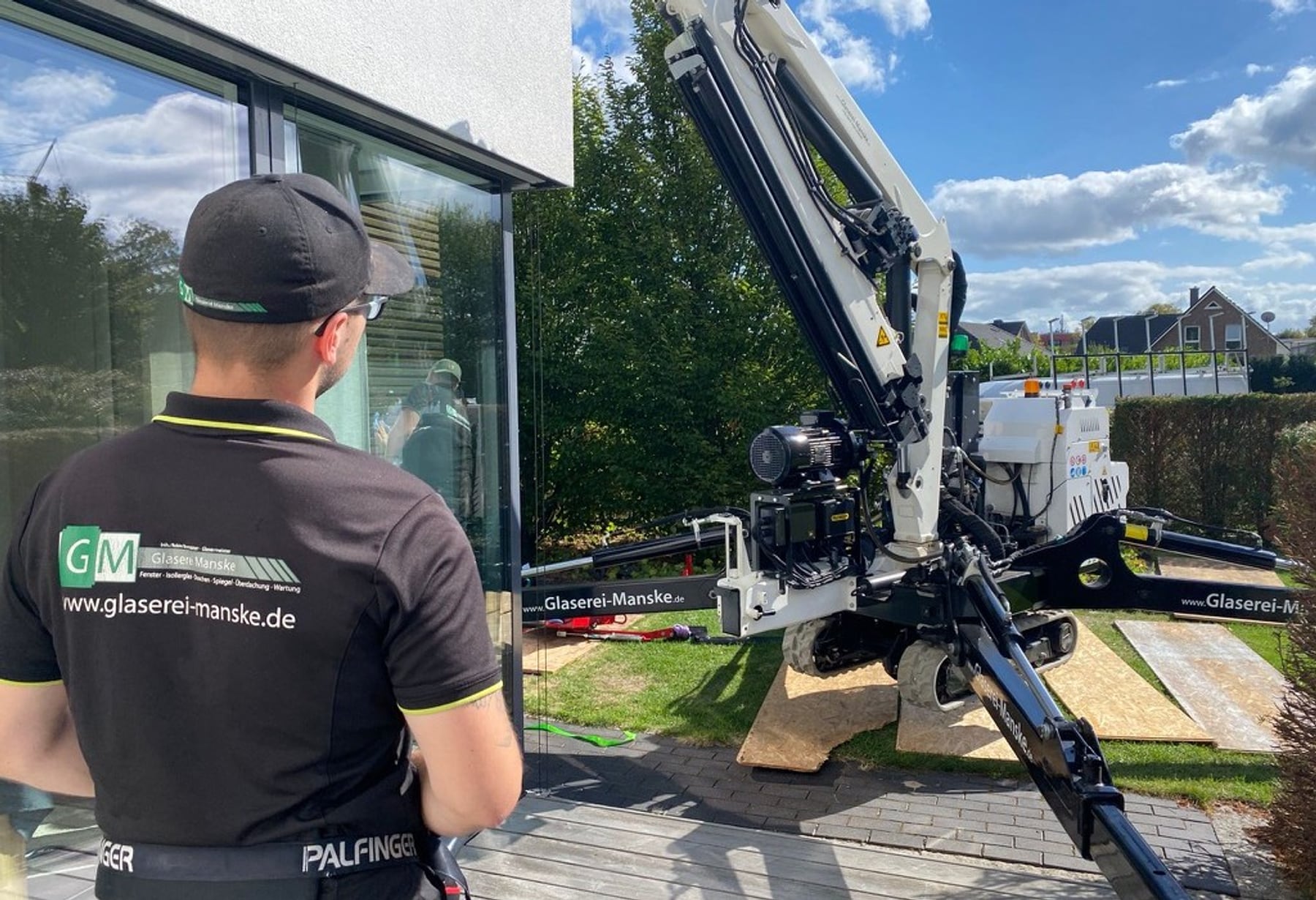 Glaser bei Fenstermontage an Gebäude mit Kran